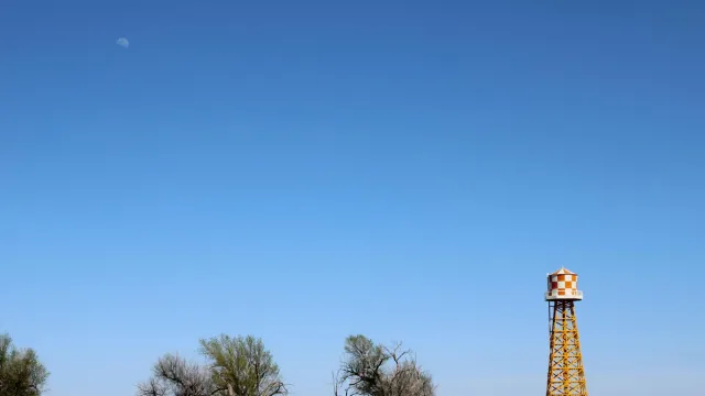 A water tower on the horizon next to trees