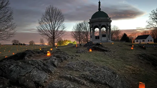 luminaries placed by Maryland Monument with dramatic orange red clouds