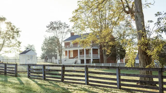A brick two story home with white pillars and railings.