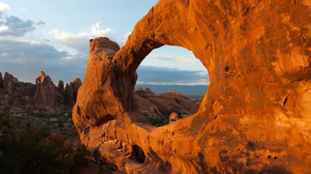 a broad, red arch with rock pinnacles in the background