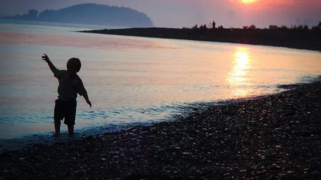 A child dancing on the beach at dusk