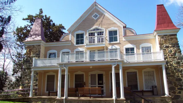 two and half story wooden frame house with double porch and stone corner posts.