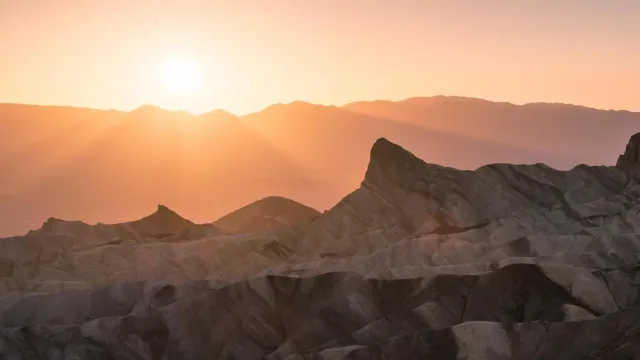 badlands bathed in pale pink and orange light from the setting sun