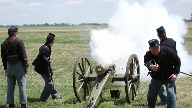 Men in 19th century U.S. Army uniforms fire a reproduction period cannon.