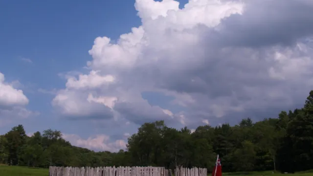 Circular stockade in the middle of a meadow. Dramatic clouds build in the blue sky.