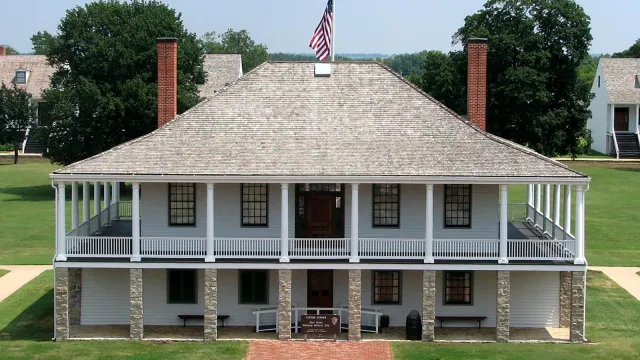 Picture of the post hospital with the parade ground and trees in the background.