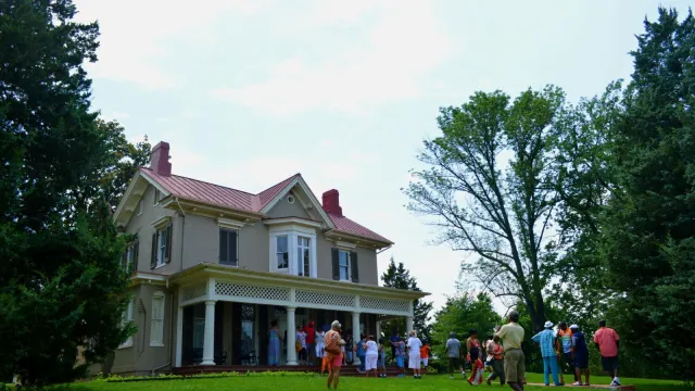 Visitors take photos in front of a historic house