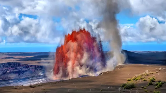 Fountains of molten lava erupting from within a crater next to a whirlwind formed from the eruption.