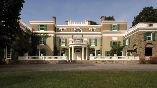 A stucco and fieldstone house with white trim and circular portico.