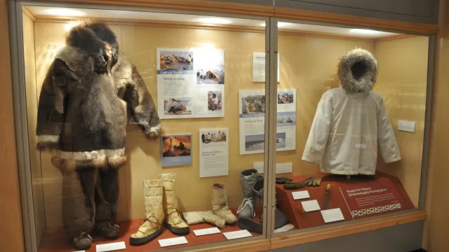 Museum exhibit case with fur parkas and boots