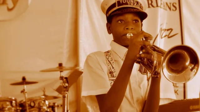 A young brass band musician plays a trumpet