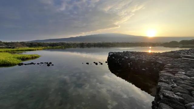 Sun rises over Hualālai volcano as seen from the Kaloko fishpond wall