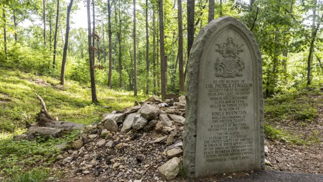 An oval gravestone for Maj Patrick Ferguson is in front of his stone covered grave.