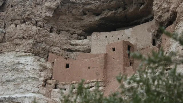 A 5-story masonry dwelling sits in a cliff alcove.