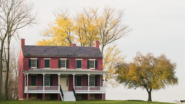 Federal style house with trees behind it during the fall season.