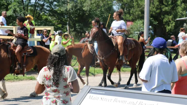 A group of people watching people on horseback during a parade