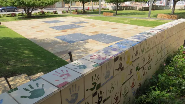 Tiles with hand prints and chalkboards set into the ground for children.