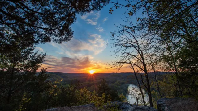 Sunset picture with high vantage point overlooking river with fall colors and sun setting in distanc
