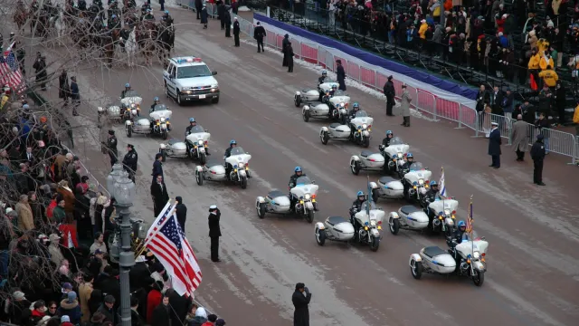 Motorcycles pass by a crowd in a parade.