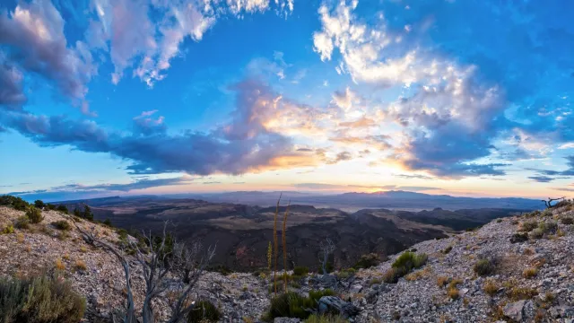 Near a cliff edge the sun sets in the distance.