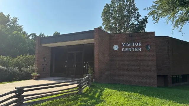Pictured is the front of the brick visitor center under a cloudless blue sky.