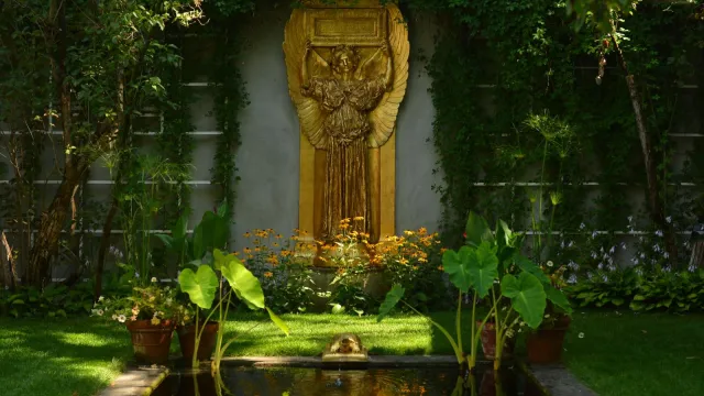 gilded statue of angel with plants and reflecting pool