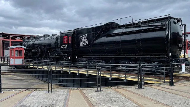 large black train with number 6039 painted in white lettering, sitting on turntable track
