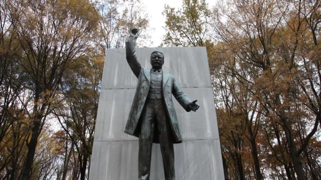 A bronze statue of Theodore Roosevelt standing and pointing.