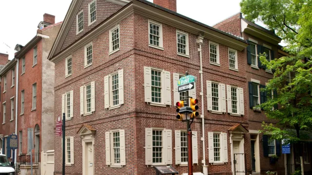 Color photo showing a three story brick rowhouse on a corner lot.