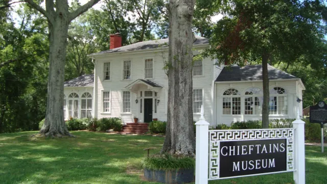 large white house, green lawn, two trees in front