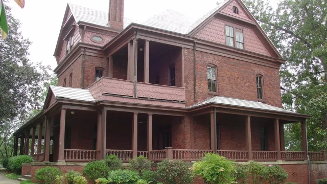 A three story Queen Anne Revival style red brick house