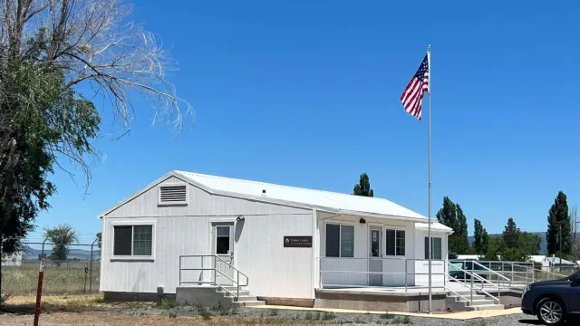 White house with a concrete deck and flag poll in the front.