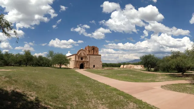 panorama of mission church with green grass and clouds