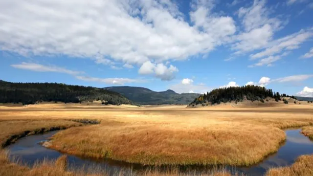 Scattered clouds over landscape view of winding river and brown grasslands