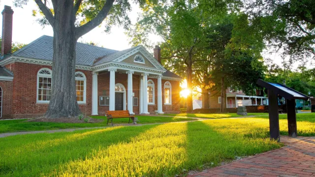 Historic Gloucester Courthouse with white columns at sunrise.