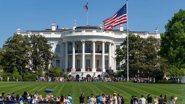 Crowds of people populate the White House South Lawn on a sunny day with the White House in view