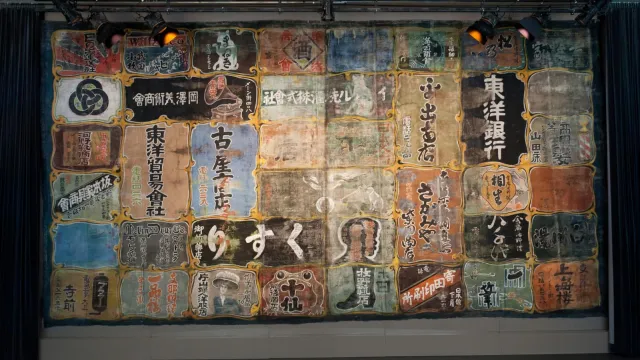 theatre curtain painted with Japanese characters advertising local businesses